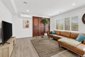 een woonkamer met een bank en een flatscreen-tv bij Palms by the sea in Saint Leonards