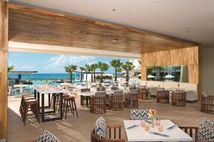 Un restaurante con mesas y sillas y el océano. en Breathless Riviera Cancun Resort & Spa - Adults Only - All inclusive, en Puerto Morelos
