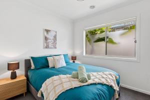 een slaapkamer met een blauw bed en een raam bij Palms by the sea in Saint Leonards