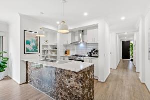 een keuken met witte kasten en een marmeren aanrecht bij Palms by the sea in Saint Leonards