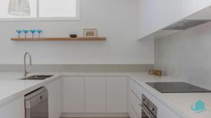 een witte keuken met witte kasten en een spoelbak bij Oceanview Beach House in Caves Beach +23 foto's