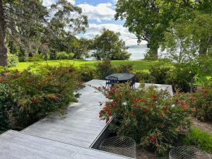 a wooden deck with a table and some flowers at wyeangta - Woodbridge Waterfront Retreat in Woodbridge
