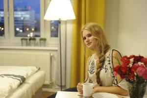 une femme assise à une table avec une tasse de café dans l'établissement Rondo Mogilskie Apartment, à Cracovie