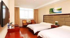 GreenTree Inn Shanghai Gongkang Road Branch في Jiangwan: غرفة فندقية بسريرين وتلفزيون