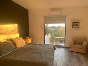 Casa del Unicornio Azul في كوكويوك: غرفة نوم بها سرير وكرسي ونافذة +15 صورة