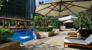 a swimming pool with an umbrella and a fountain at Putian Depo Hotel in Putian