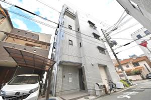 a white car parked in front of a building at LIJ Stay Morinomiya 5BedRooms in Osaka