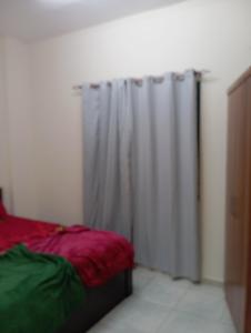 a bedroom with a bed and a shower curtain at Cozy room in Sharjah