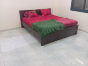 a bed with red and green sheets in a room at Cozy room in Sharjah