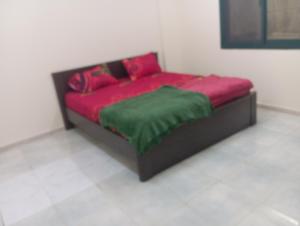 a bed with red and green pillows in a room at Cozy room in Sharjah