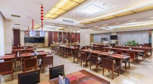 a restaurant with wooden tables and chairs in a room at Huizhou Wanyun Holiday Hotel in Huangshan