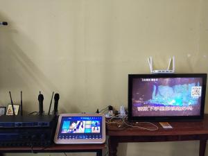 a laptop computer and a television on a table at Village House With River View And Karaoke 8 to10 Pax in Jeram