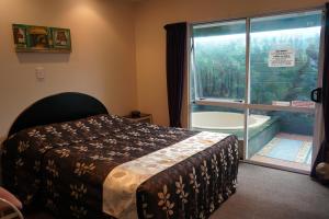 a bedroom with a bed and a tub next to a window at Ascot On Fenton in Rotorua
