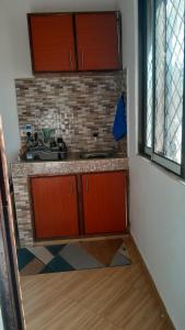 Little Haven في ماليندي: مطبخ مع خزائن بنية وجدار من الطوب +صورة واحدة