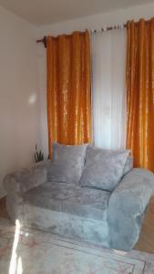 Little Haven في ماليندي: أريكة في غرفة المعيشة مع ستارة برتقالية