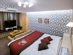 a bedroom with a large bed and a flat screen tv at Kumamoto Hotel Christmas Forest Garden (Love Hotel) in Shimo-koga