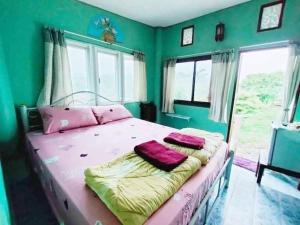 a bedroom with a bed with green walls and windows at หมอกอิงธาร รีสอร์ท เขาค้อ in Ban Khao Ya Nua