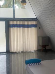 uma sala com um sofá, uma TV e uma cortina em The Banana Cottage em Udawalawe