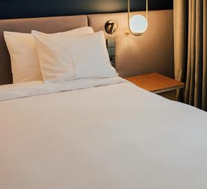 uma cama com lençóis e travesseiros brancos em um quarto em The Banana Cottage em Udawalawe