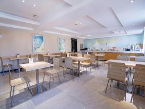 City Comfort Inn Yichang Gezhouba CBD Shopping Center في ييتشانغ: مطعم به طاولات وكراسي ومنضدة