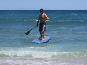 a man standing on a paddle board in the ocean at Kymata by Anastasia in Stavros