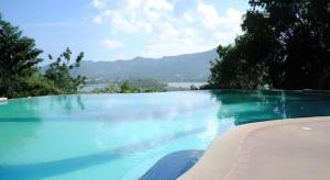 Baan Suan Sook Resort في شاطئ تشاوينغ: مسبح ازرق كبير مطل على الماء