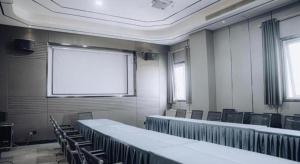 a room with tables and chairs and a projection screen at Jinjiang Metropolo Hotel Nanjing Jiangning Binjiang Development Zone in Qingxiu
