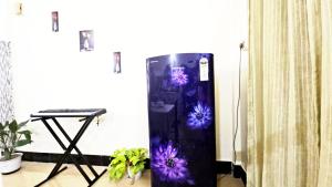 Tomato home stay في Tezpur: ثلاجة سوداء في غرفة مزينة بالزهور