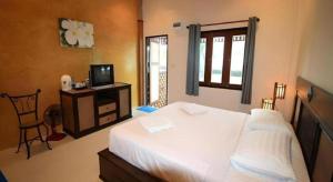 a bedroom with a white bed and a television at Pilton Resort in Ban Huai Yang