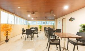 Treebo Elite Inn في تشيناي: غرفة طعام مع طاولات وكراسي ونوافذ