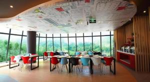 a restaurant with tables and chairs and a large window at Ibis Ya An Langqiao in Shaping