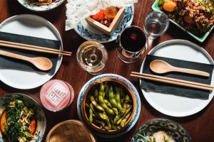 a wooden table topped with plates of food and chopsticks at STORY HOTEL STOCKHOLM STUREPLAN, in JdV by Hyatt in Stockholm