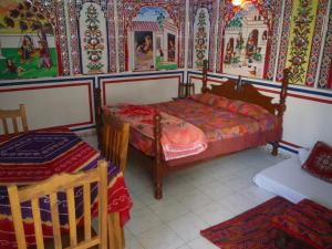 曼达瓦Hotel Shekhawati, A boutique stay的卧室配有一张床,墙上挂有绘画作品