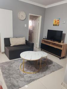 Ekukhanyeni Guest house في Kwaluseni: غرفة معيشة مع أريكة وطاولة قهوة