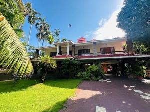 a large white house with a porch and a yard at Vineyard Vacations in Cochin