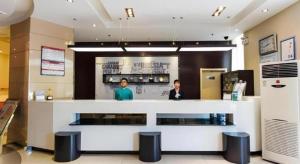 two people standing at a counter in a restaurant at Jinjiang Inn Zibo People's Park Liuquan Road in Zibo