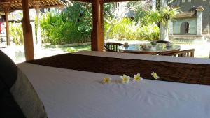 a table with three flowers on it with a table with at Puri Kutat Lestari in Sanur