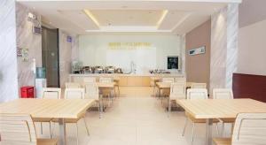 City Comfort Inn Zhanjiang Shimao Building Chikan Old Street في Tchia-k'am: كافتيريا بطاولات وكراسي خشبية ومطبخ