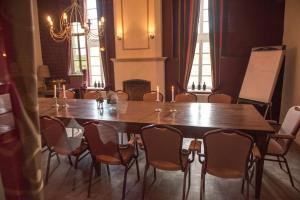 a wooden table and chairs in a room with a fireplace at Hotel Schinvelder Hoeve in Schinveld