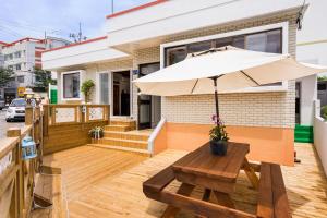 eine Terrasse mit einer Bank und einem Sonnenschirm in der Unterkunft Yours Guesthouse in Tongyeong in Tongyeong