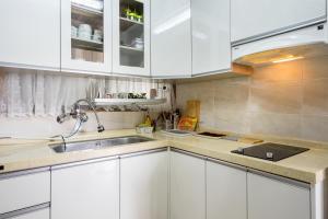 uma cozinha com armários brancos e um lavatório em Yours Guesthouse in Tongyeong em Tongyeong
