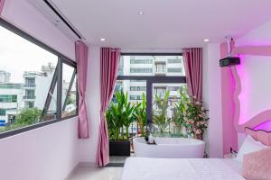 a pink bedroom with a tub and a large window at Ori Home in Ho Chi Minh City