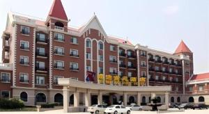 a large brick building with cars parked in front of it at Grand New Century Hotel Binhai Tianjin in Binhai