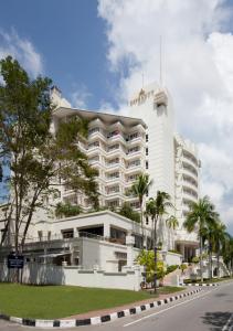 納閩的住宿－納閩帝盛君豪酒店，一座白色的大建筑,前面有棕榈树