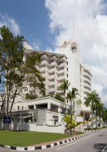 a large white building with palm trees in front of it at Dorsett Grand Labuan in Labuan