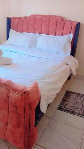 ein großes Bett mit einer roten Couch daneben in der Unterkunft Blossom's homes-Muthiga, one bedroom in Rungiri