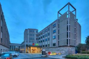 a large building in a parking lot with a car at New Century Manju Hotel Shanghai New International Expo Center in Shanghai