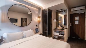 a bedroom with a large white bed and a mirror at Hôtel Kyriad Brive Ouest in Brive-la-Gaillarde