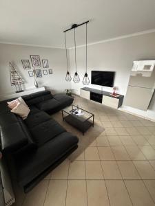 a living room with a black couch and a flat screen tv at Antweiler Ferienwohnung in Bleialf