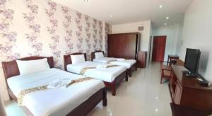 a hotel room with three beds and a television at Doungta Anda Hotel Krabi in Ban Khlong Chi Lat
